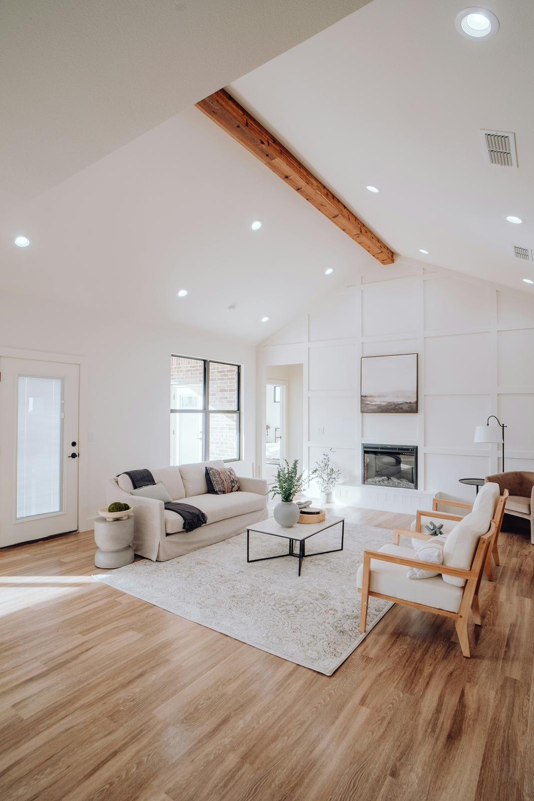 A bright, freshly cleaned open-plan living room with vaulted ceiling and wood floors